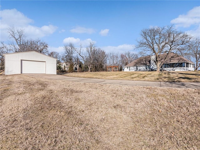 view of yard featuring a garage, driveway, and an outdoor structure