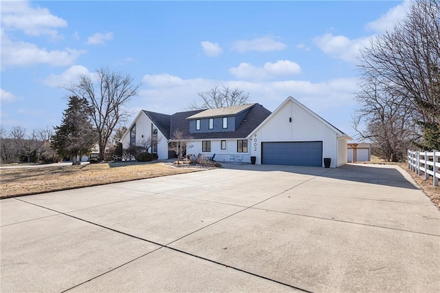 modern farmhouse featuring a garage, concrete driveway, and fence