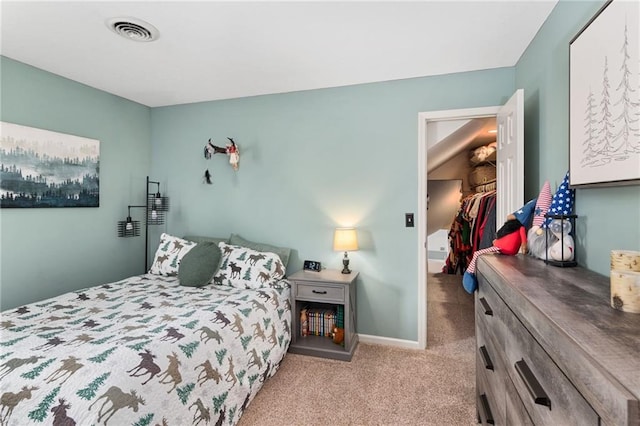 carpeted bedroom with baseboards, visible vents, and a walk in closet