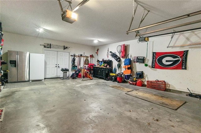 garage featuring a garage door opener, freestanding refrigerator, and stainless steel fridge with ice dispenser