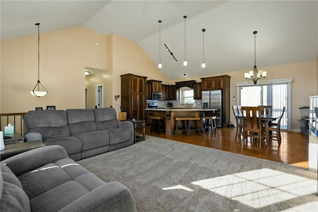 living room with dark wood-type flooring, high vaulted ceiling, plenty of natural light, and an inviting chandelier