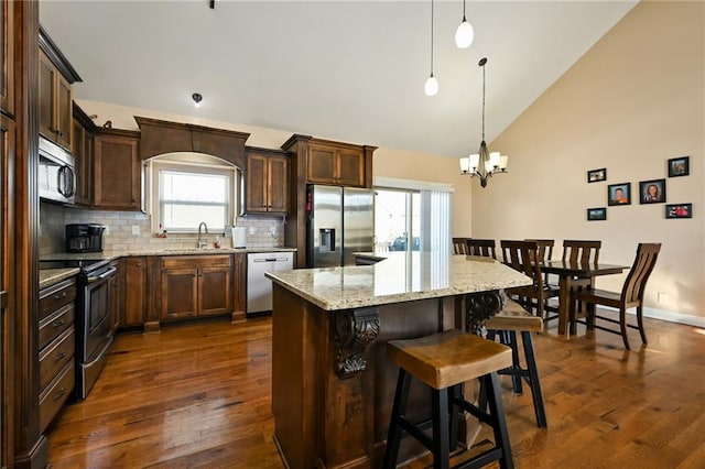 kitchen with a sink, a center island, dark wood-style floors, and stainless steel appliances