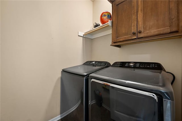 clothes washing area with baseboards, cabinet space, and washer and clothes dryer