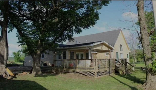 back of property featuring a deck and a lawn