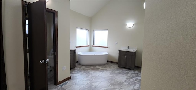 bathroom featuring vanity, vaulted ceiling, and a tub