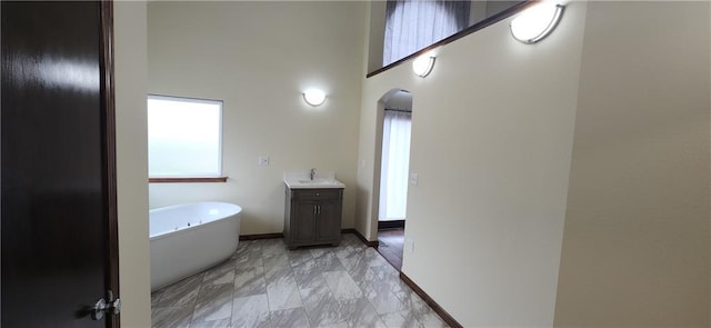 bathroom featuring a towering ceiling, vanity, and a tub