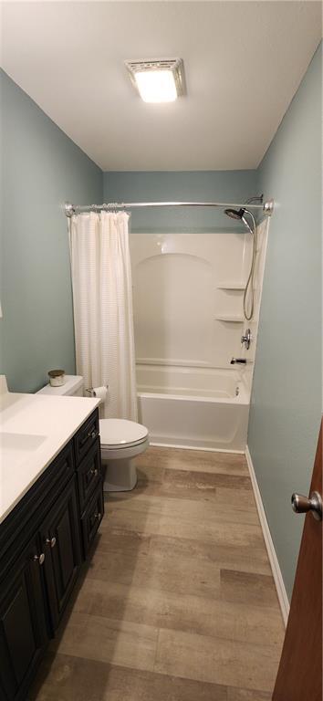 full bathroom featuring vanity, hardwood / wood-style floors, shower / bath combination with curtain, and toilet
