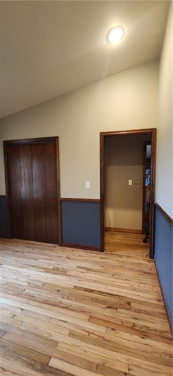 unfurnished bedroom with lofted ceiling and light hardwood / wood-style floors