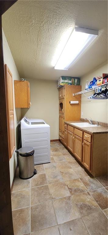 washroom featuring washer / clothes dryer, sink, cabinets, and a textured ceiling