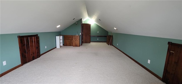 bonus room with vaulted ceiling and light colored carpet