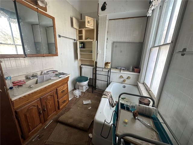 bathroom with toilet, vanity, and a tub to relax in