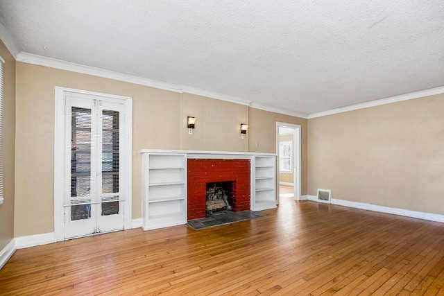 unfurnished living room featuring ornamental molding, wood-type flooring, a brick fireplace, and a textured ceiling