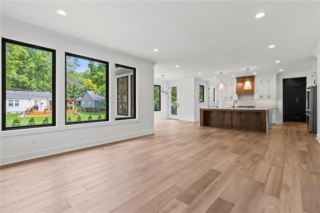 unfurnished living room with sink and light hardwood / wood-style floors