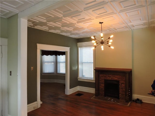 unfurnished living room with a chandelier, a fireplace, and dark hardwood / wood-style flooring