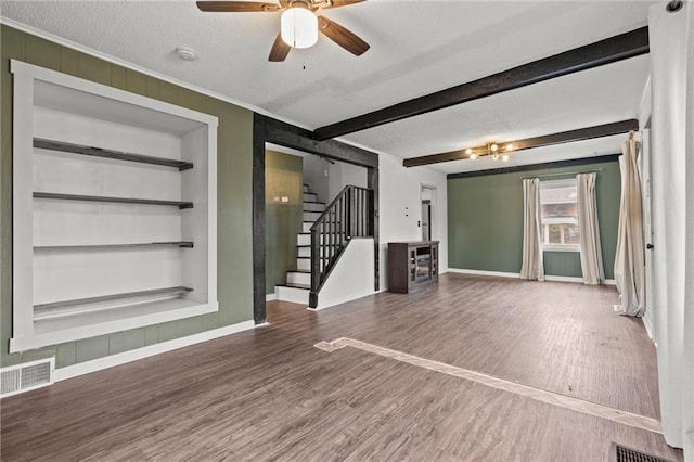 spare room featuring beam ceiling, dark wood-type flooring, built in features, and a textured ceiling