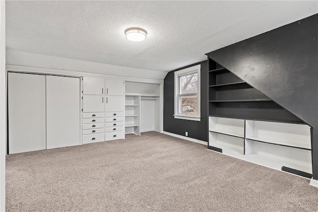 unfurnished bedroom featuring vaulted ceiling, light colored carpet, a closet, and a textured ceiling