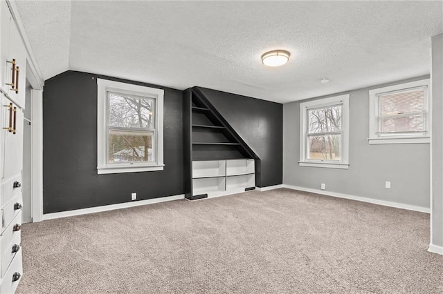 carpeted empty room featuring lofted ceiling and a textured ceiling