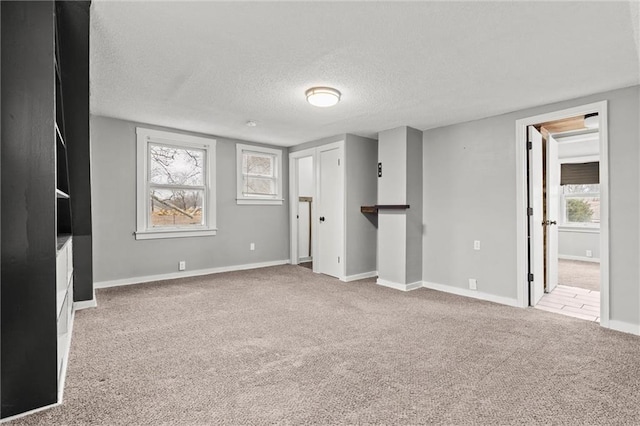 basement with a healthy amount of sunlight, light colored carpet, and a textured ceiling