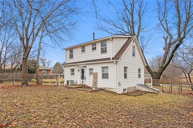 rear view of property with central AC unit and a lawn