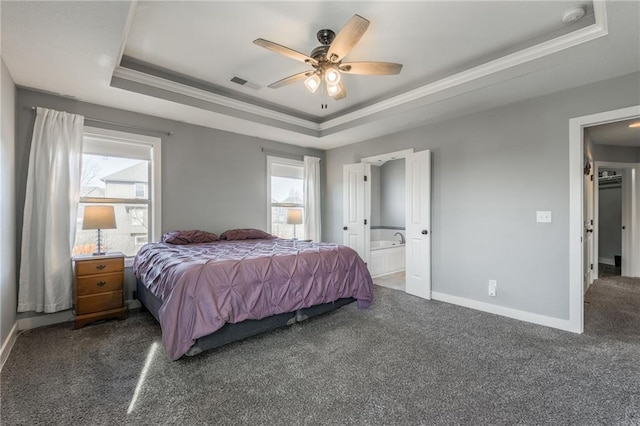 bedroom with crown molding, a tray ceiling, ensuite bath, and dark colored carpet