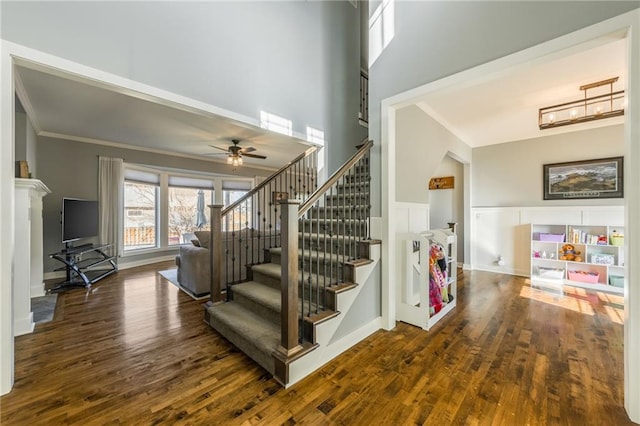 stairway with crown molding, wood-type flooring, and a high ceiling