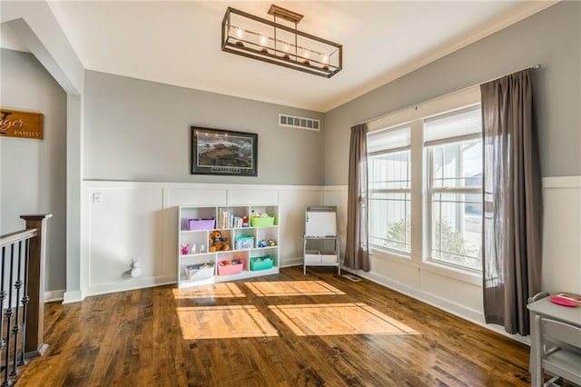 game room with crown molding, hardwood / wood-style floors, and an inviting chandelier