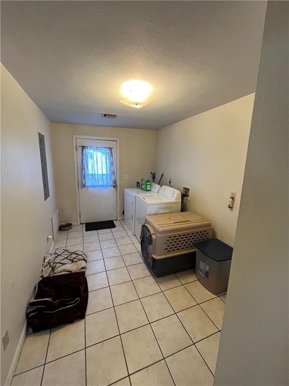 tiled bedroom with washing machine and dryer and a textured ceiling