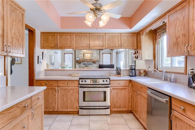 kitchen featuring sink, ceiling fan, appliances with stainless steel finishes, light tile patterned flooring, and a raised ceiling