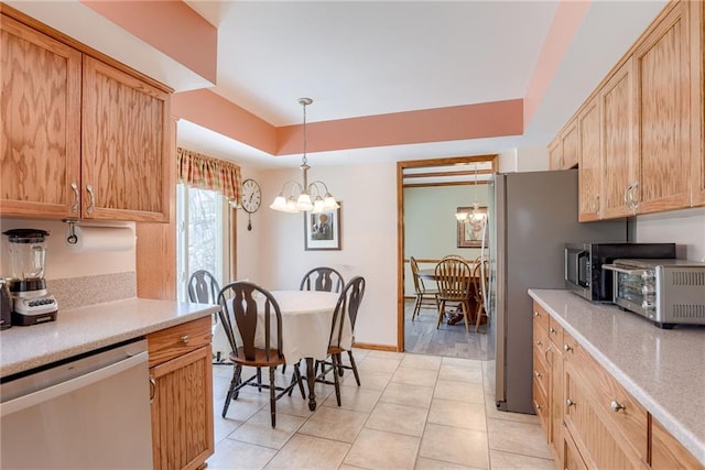 kitchen with light tile patterned floors, hanging light fixtures, stainless steel appliances, a notable chandelier, and a tray ceiling