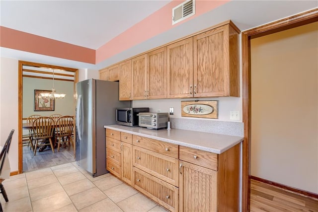 kitchen with pendant lighting, a chandelier, light tile patterned floors, stainless steel appliances, and light brown cabinets