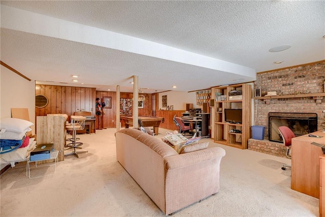 carpeted living room with wooden walls, pool table, a textured ceiling, and a fireplace