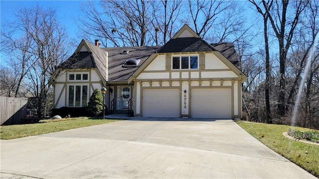 tudor home with a garage, concrete driveway, and stucco siding