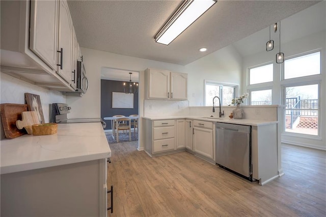 kitchen featuring sink, white cabinetry, hanging light fixtures, stainless steel appliances, and light hardwood / wood-style floors