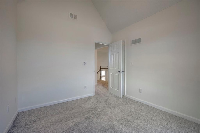 spare room featuring light colored carpet and high vaulted ceiling