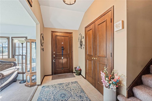 foyer entrance with lofted ceiling, stairway, baseboards, and light tile patterned floors