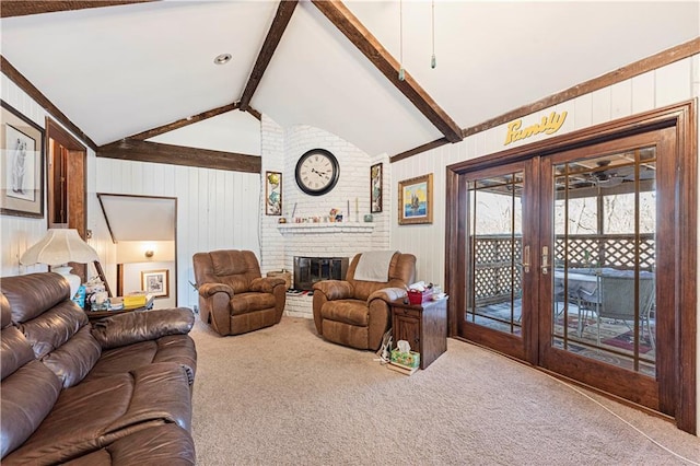 living area featuring carpet floors, french doors, lofted ceiling with beams, a brick fireplace, and wooden walls