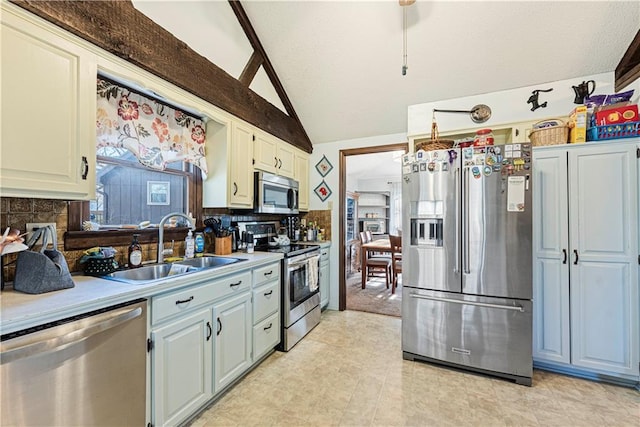 kitchen featuring lofted ceiling, appliances with stainless steel finishes, backsplash, and a sink