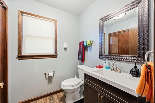 bathroom with toilet, baseboards, wood finished floors, and vanity