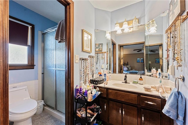 full bathroom featuring toilet, a stall shower, ceiling fan, vanity, and ensuite bath