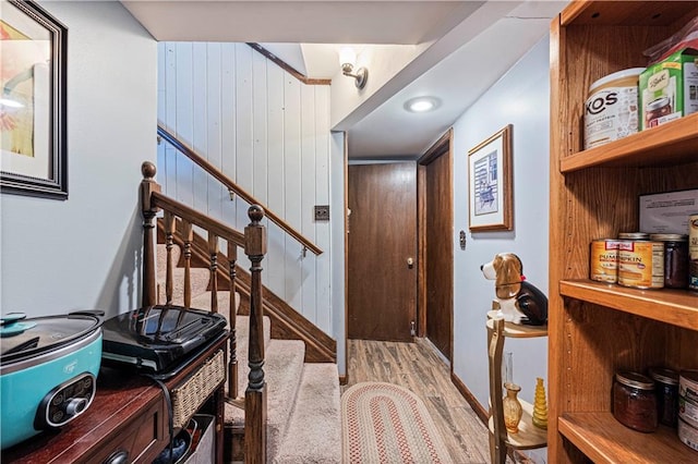 interior space featuring light wood-type flooring, wood walls, and stairway