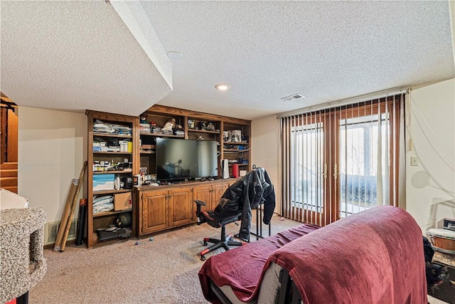 bedroom featuring light carpet, visible vents, and a textured ceiling