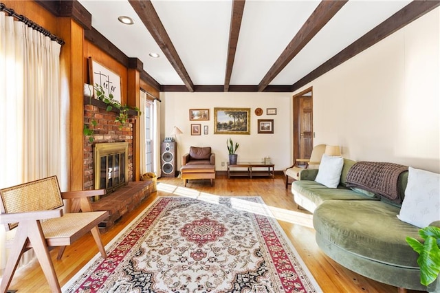 living room with beamed ceiling, a fireplace, and light hardwood / wood-style floors