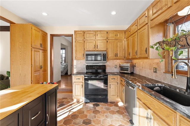 kitchen featuring tasteful backsplash, sink, dark stone countertops, and appliances with stainless steel finishes