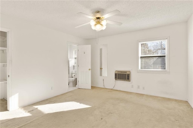 empty room featuring ceiling fan, light colored carpet, an AC wall unit, and a textured ceiling