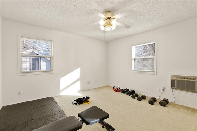 exercise room featuring ceiling fan, an AC wall unit, a textured ceiling, and carpet flooring