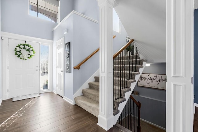 entrance foyer with a wealth of natural light, dark wood-type flooring, decorative columns, and a high ceiling