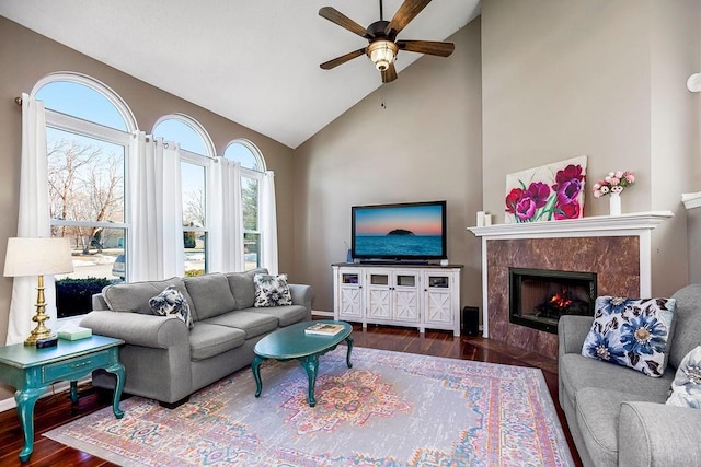 living room with dark wood-type flooring, ceiling fan, a premium fireplace, and high vaulted ceiling