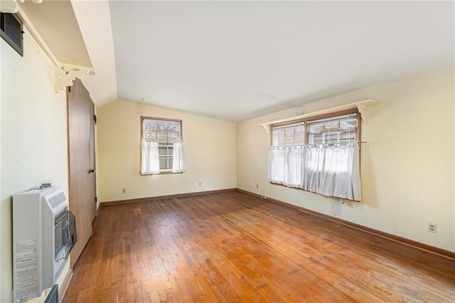 unfurnished living room with hardwood / wood-style floors, lofted ceiling, and heating unit