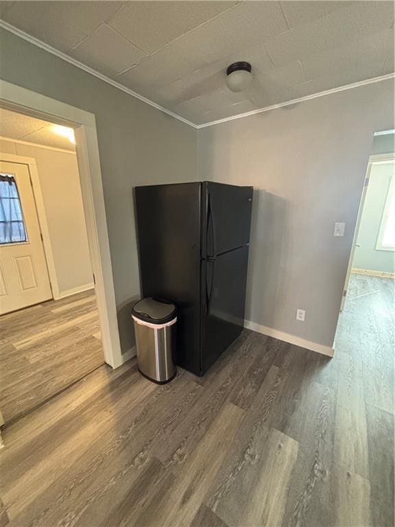 kitchen featuring hardwood / wood-style floors, ornamental molding, a healthy amount of sunlight, and black fridge