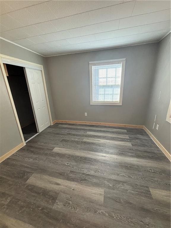 unfurnished bedroom with dark hardwood / wood-style floors and a closet